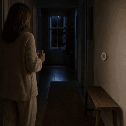 Frau betritt den dunklen Flur und das LumiBeam Nachtlicht schaltet sich per Bewegungsmelder ein