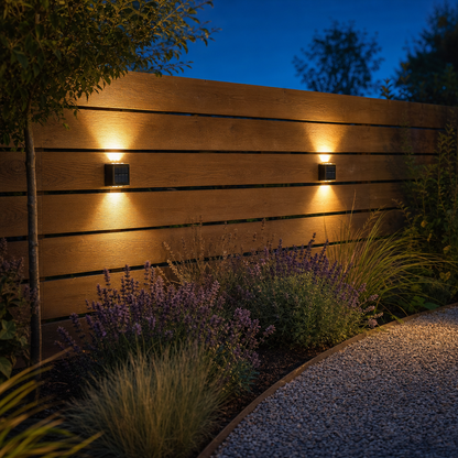 Zwei SolarGlow Solarleuchten am Gartenzaun in der Dämmerung